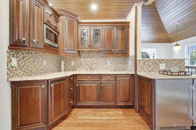 kitchen with wood ceiling, stainless steel microwave, decorative backsplash, light wood-type flooring, and vaulted ceiling