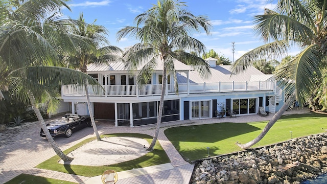 back of house featuring a balcony, a yard, and a sunroom