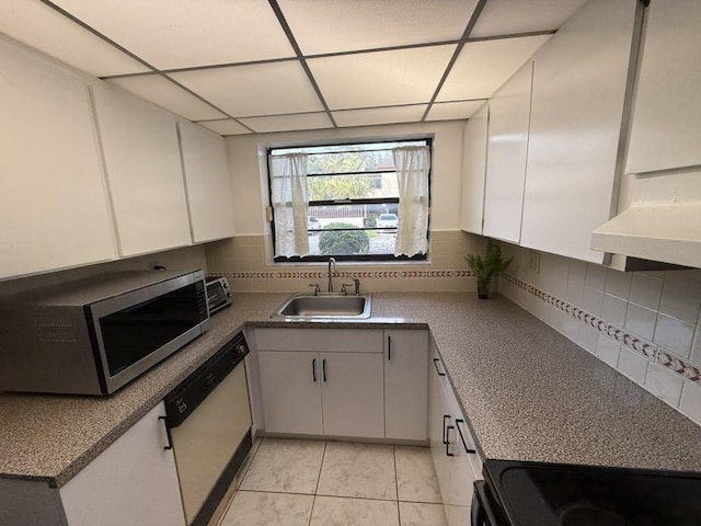 kitchen with tasteful backsplash, stainless steel microwave, a sink, white dishwasher, and a drop ceiling