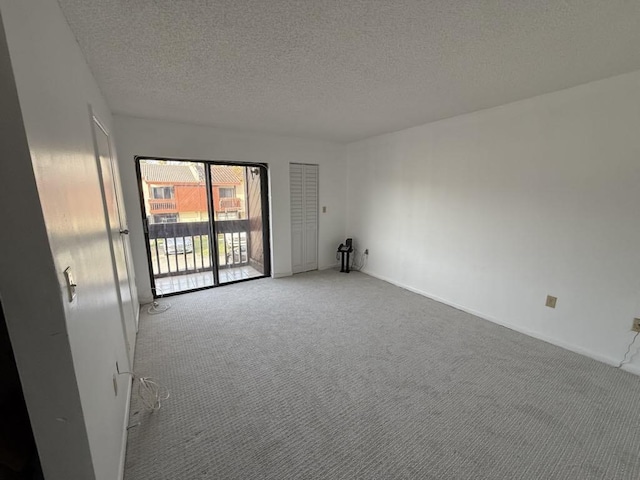 carpeted spare room featuring a textured ceiling and baseboards