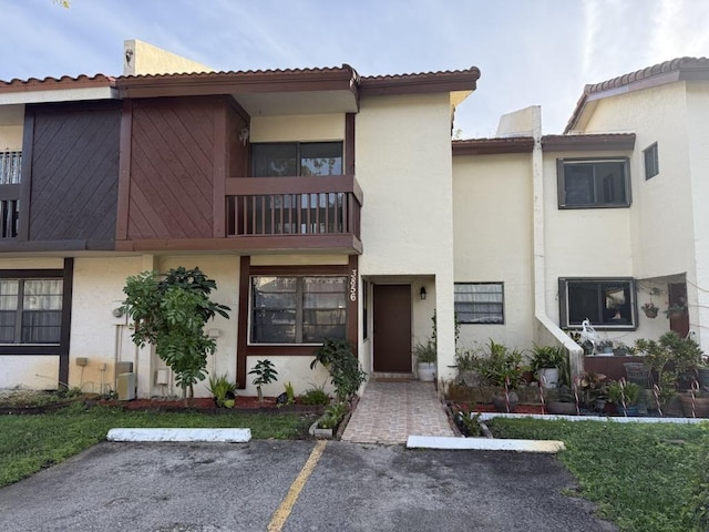 multi unit property featuring a balcony, uncovered parking, and stucco siding