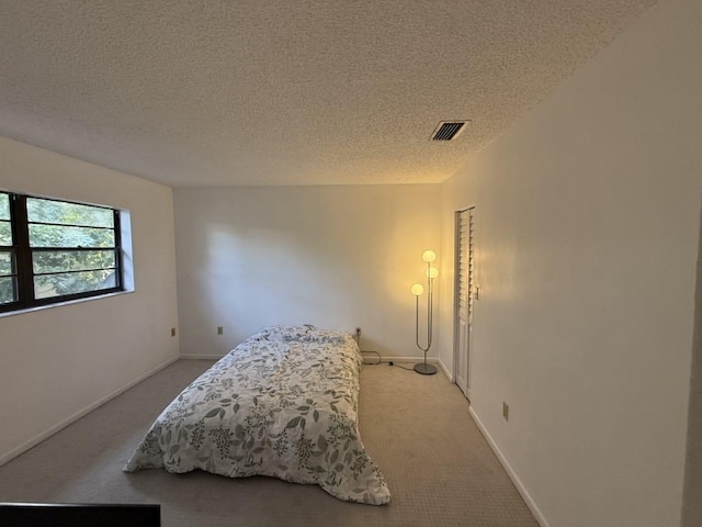 bedroom featuring light carpet, visible vents, and a textured ceiling