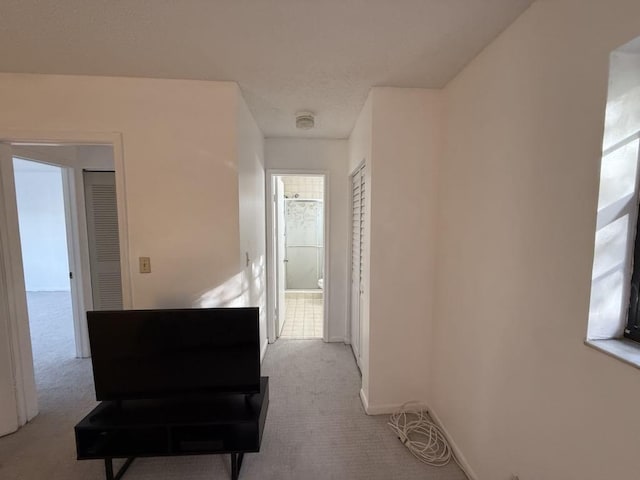 corridor featuring carpet floors, baseboards, and a textured ceiling