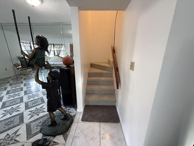 stairs with a textured ceiling and baseboards