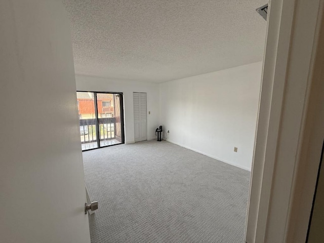 spare room with carpet, baseboards, and a textured ceiling