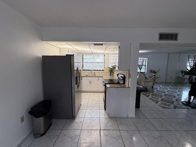 kitchen with electric range, visible vents, stainless steel fridge with ice dispenser, white cabinetry, and a sink