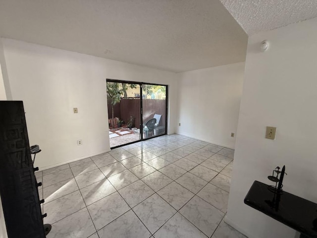 spare room featuring a textured ceiling and light tile patterned floors