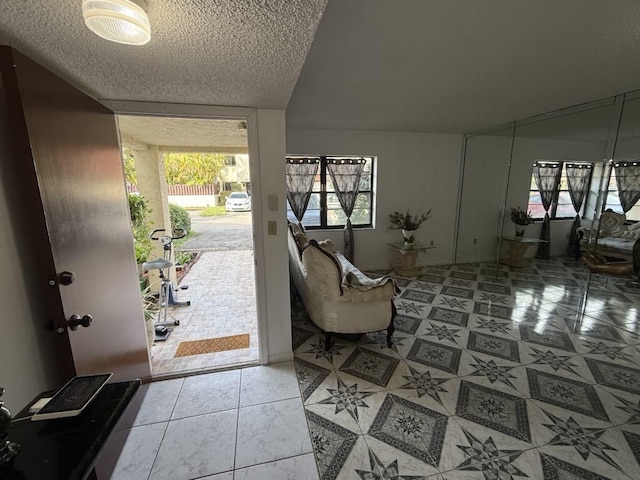 entryway featuring tile patterned flooring, a wall of windows, and a textured ceiling