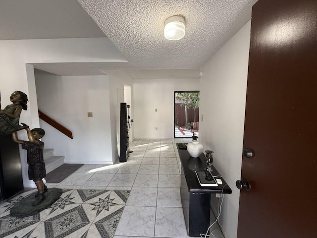 foyer entrance with marble finish floor, a textured ceiling, and stairs