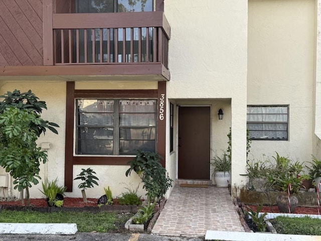 property entrance featuring a balcony and stucco siding