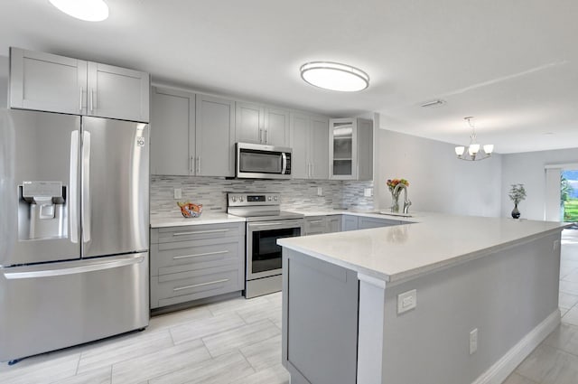 kitchen featuring backsplash, stainless steel appliances, light countertops, and gray cabinetry