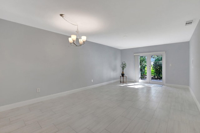 spare room with a chandelier and french doors