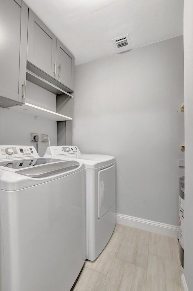 clothes washing area featuring washer and dryer and cabinets