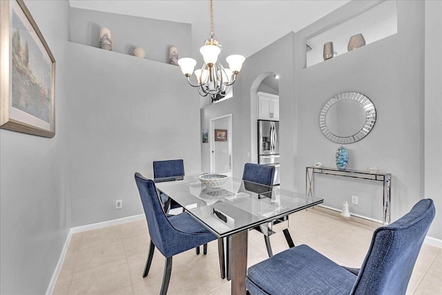 tiled dining space featuring a high ceiling and a chandelier