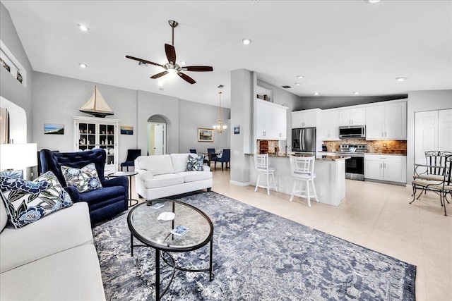 living room featuring ceiling fan with notable chandelier and lofted ceiling