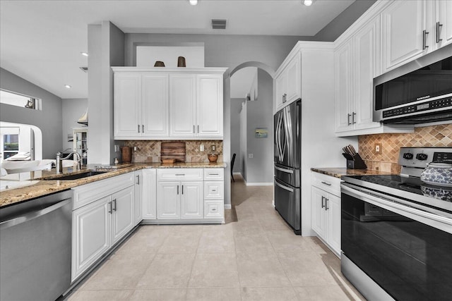 kitchen featuring light stone counters, white cabinets, and stainless steel appliances