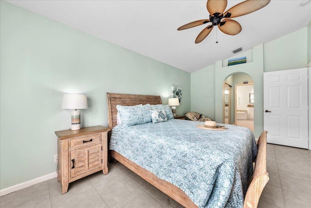 tiled bedroom with connected bathroom, vaulted ceiling, and ceiling fan