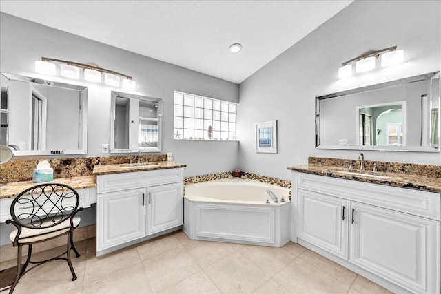 bathroom with a washtub, vanity, vaulted ceiling, and tile patterned flooring