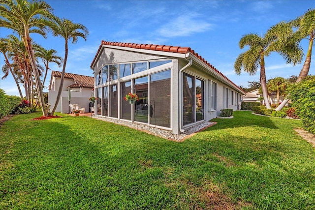 back of house with a lawn and a sunroom