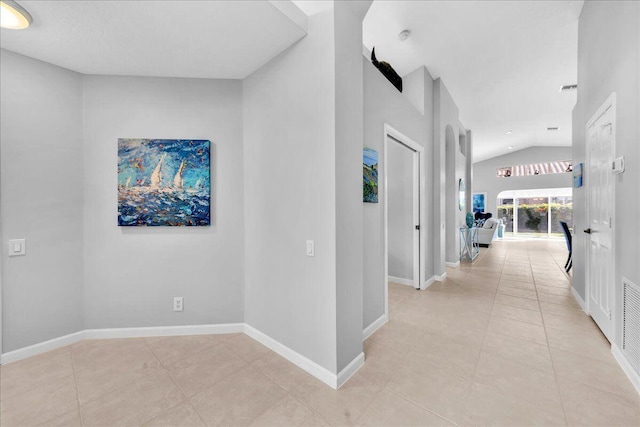 hallway featuring lofted ceiling and light tile patterned floors