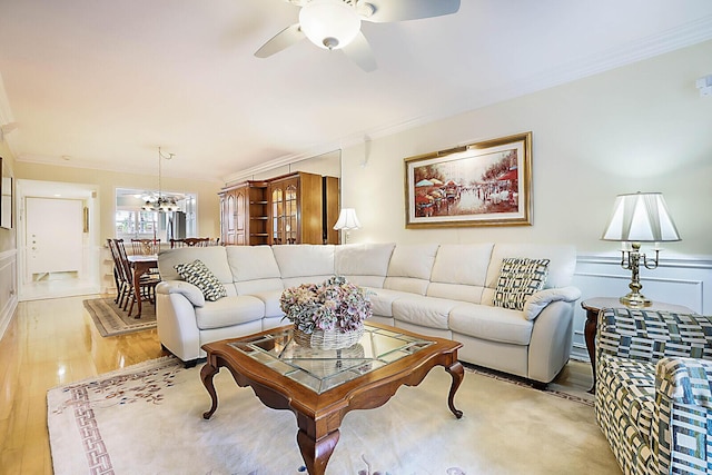 living room featuring ceiling fan with notable chandelier, light hardwood / wood-style floors, and ornamental molding