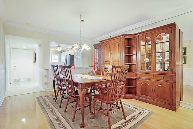 dining space featuring crown molding, ceiling fan with notable chandelier, and light wood-type flooring