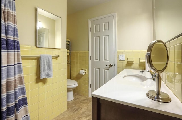 bathroom featuring vanity, tile walls, and toilet