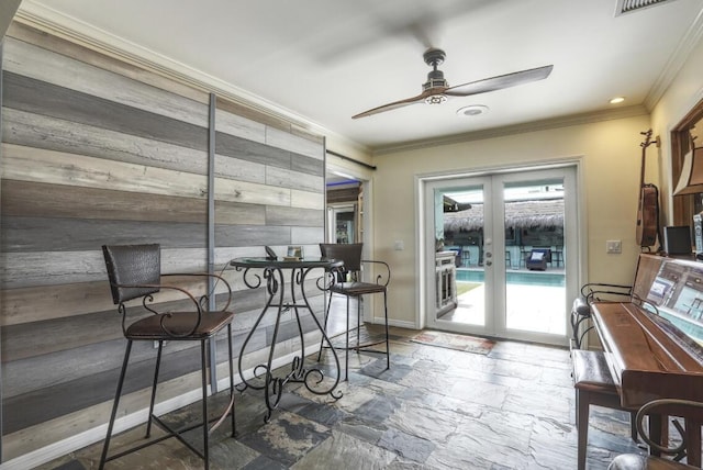 dining space featuring ceiling fan, wood walls, and crown molding