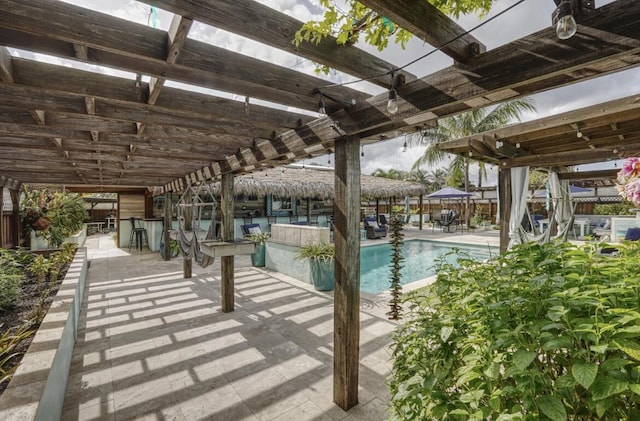 view of swimming pool featuring a pergola, an outdoor bar, and a patio