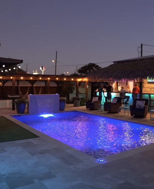 pool at dusk featuring a patio area