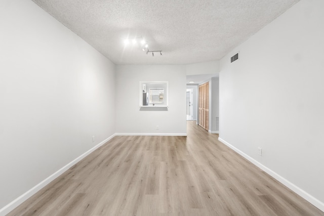 empty room with light hardwood / wood-style floors and a textured ceiling