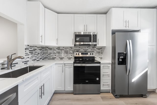 kitchen featuring tasteful backsplash, sink, white cabinets, and appliances with stainless steel finishes