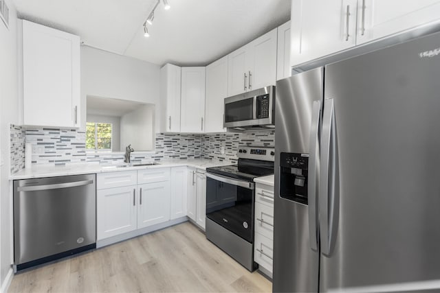 kitchen featuring backsplash, stainless steel appliances, sink, light hardwood / wood-style flooring, and white cabinetry