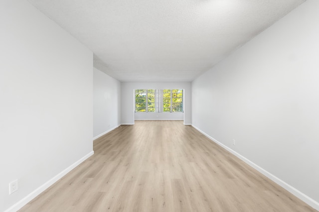 unfurnished room featuring light wood-type flooring and a textured ceiling