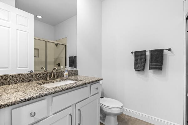 bathroom with tile patterned floors, vanity, toilet, and a shower with shower door