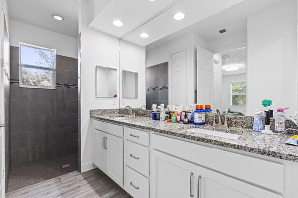 bathroom featuring tiled shower, hardwood / wood-style floors, and vanity