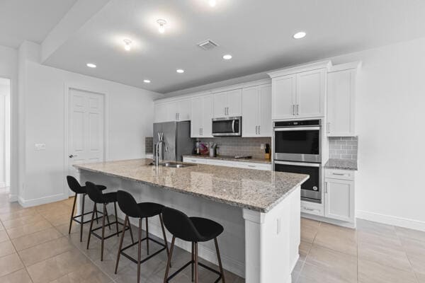 kitchen with a center island with sink, white cabinetry, and appliances with stainless steel finishes