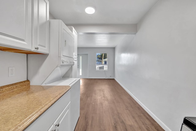 kitchen with cooling unit, wood-type flooring, white cabinetry, and stacked washer and clothes dryer