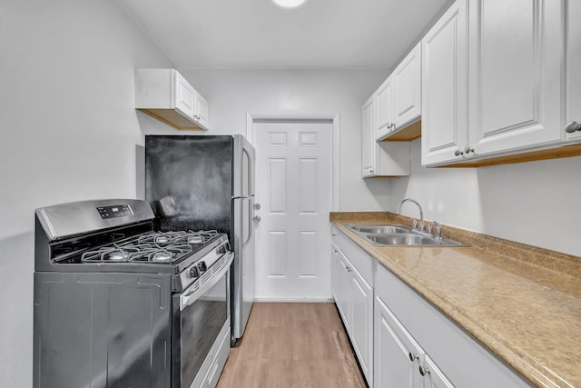 kitchen featuring gas range, white cabinetry, sink, and light hardwood / wood-style floors