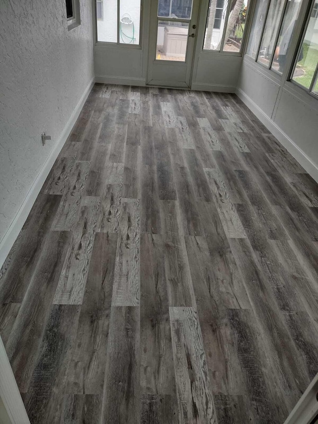 empty room with plenty of natural light and dark wood-type flooring