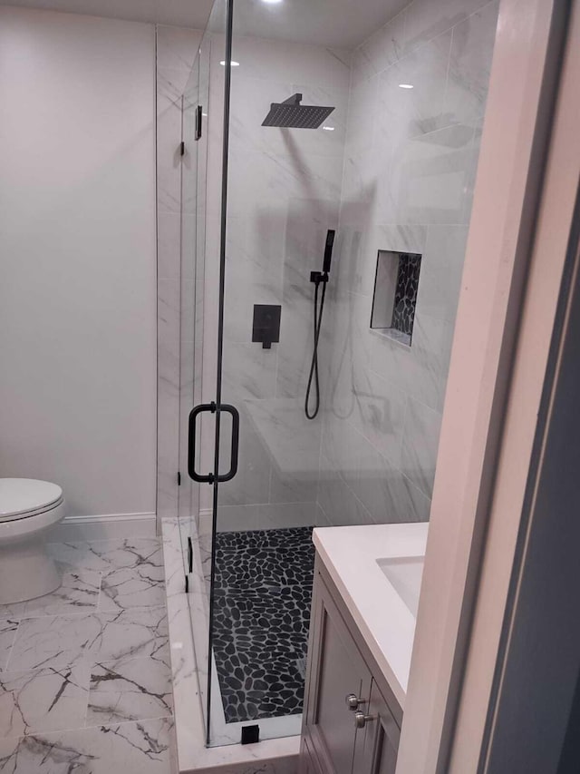 bathroom featuring vanity, a shower with shower door, and toilet