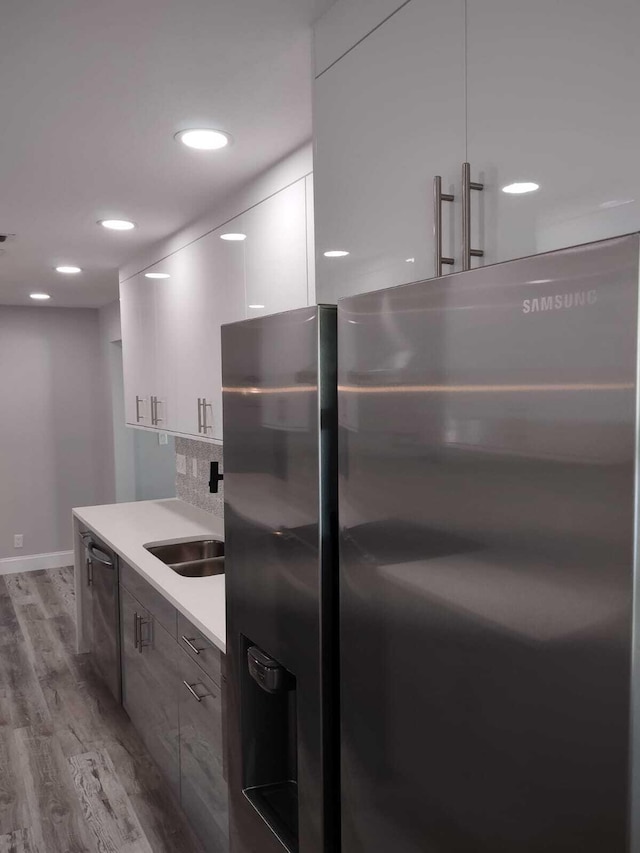 kitchen with sink, stainless steel appliances, tasteful backsplash, light hardwood / wood-style flooring, and white cabinets