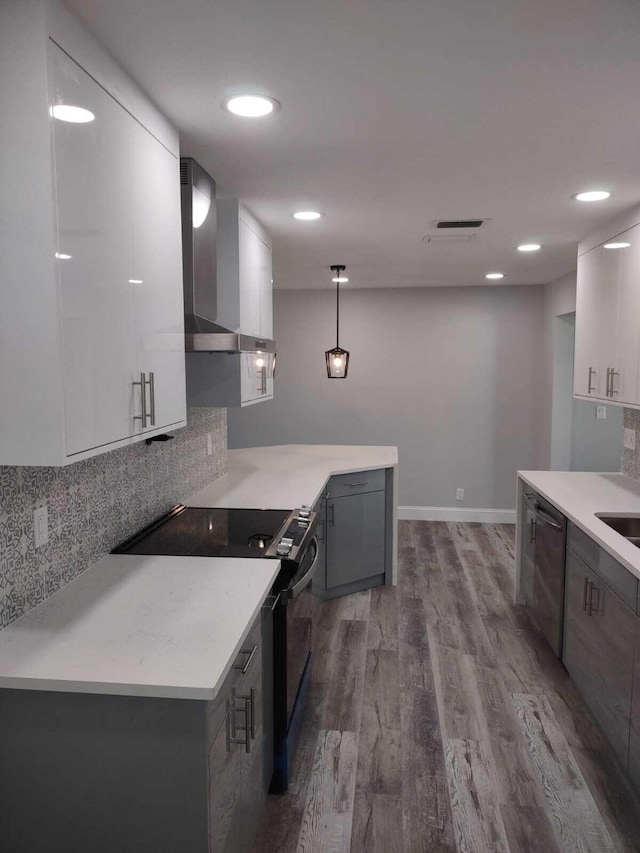 kitchen with wall chimney range hood, decorative light fixtures, dishwasher, white cabinets, and range