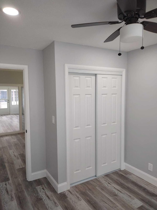 unfurnished bedroom featuring dark hardwood / wood-style flooring, a closet, and ceiling fan