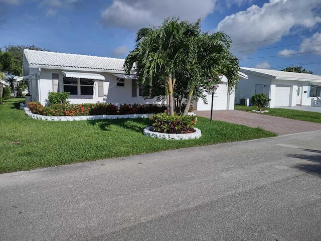 ranch-style house featuring a garage and a front lawn