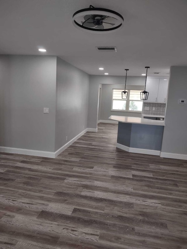 kitchen with backsplash, dark hardwood / wood-style flooring, white cabinets, and decorative light fixtures