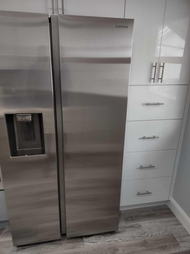 details featuring white cabinets, stainless steel refrigerator with ice dispenser, and hardwood / wood-style flooring