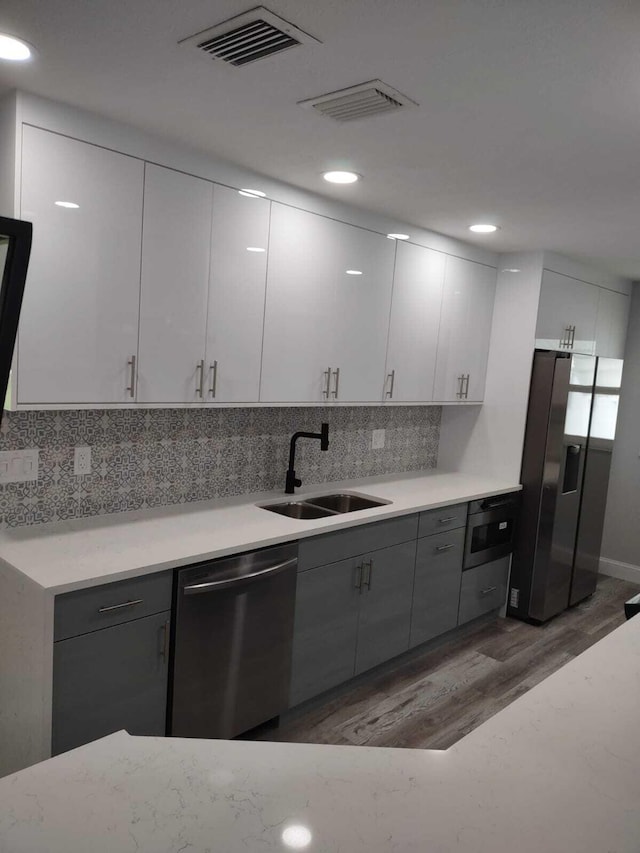 kitchen with white cabinetry, sink, dark wood-type flooring, stainless steel appliances, and gray cabinets