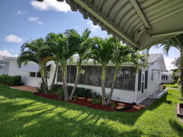 view of property exterior with a sunroom and a yard