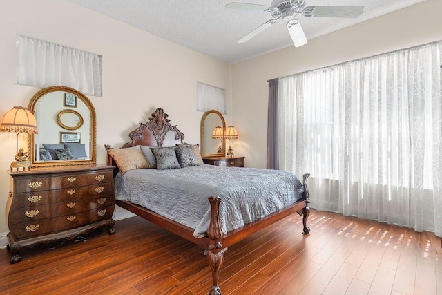 bedroom with hardwood / wood-style flooring, ceiling fan, and a textured ceiling